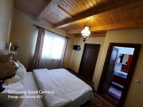 a bedroom with a white bed and a window at Pensiunea Valea Branzei in Năneşti