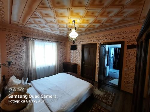 a bedroom with a bed and a window and a ceiling at Pensiunea Valea Branzei in Năneşti