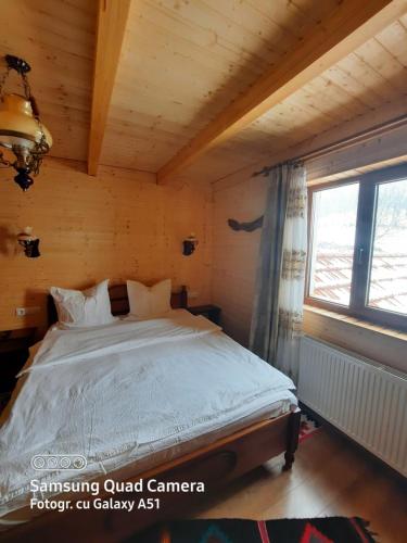 a bedroom with a bed in a wooden room at Pensiunea Valea Branzei in Năneşti