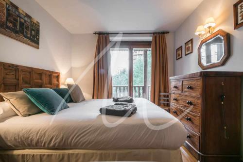 a bedroom with a bed with a dresser and a window at Amitges by SeaMount Rentals in Baqueira-Beret