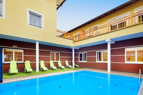 a swimming pool in front of a building with chairs at Hotel der Wolkensteinbär in Bramberg am Wildkogel