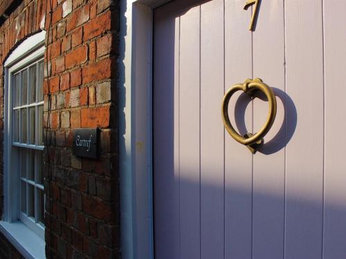 a purple door with a heart shaped door knocker on it at Cartref in Farnham
