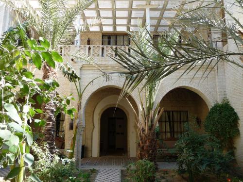 a building with a palm tree in the courtyard at Dar Tozeur in Tozeur