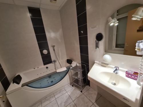 La salle de bains est pourvue d'une baignoire et d'un lavabo. dans l'établissement HOSTELLERIE du CANTAL, à Murat