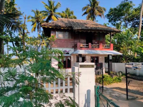 a house with a thatched roof and a refrigerator at Cherai Beach Retreat in Cherai Beach