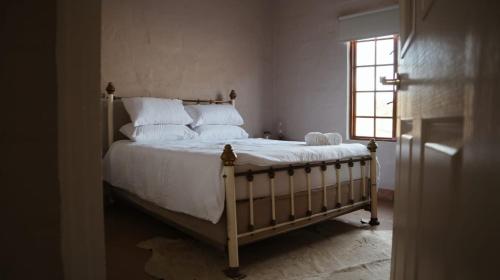 1 dormitorio con 1 cama con sábanas blancas y ventana en Riverstone Game Farm, en Ladismith