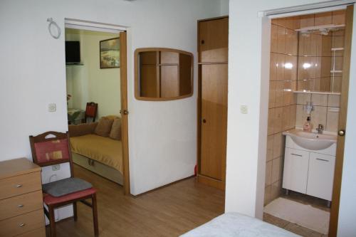 a bathroom with a sink and a couch in a room at Apartmani Mijatović in Lopar