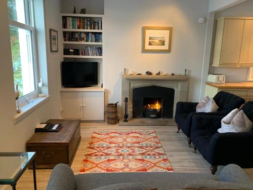 a living room with a fireplace with couches and a tv at Tigh Beg Croft in Lerags
