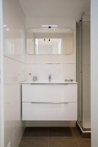 une salle de bain avec un lavabo blanc et un miroir dans l'établissement F2 TERRASSE, MODERNE, HYPER CENTRE, CLIM, ASCENSEUR- dubouchage, à Nice