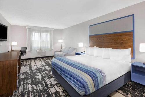 a hotel room with a large bed and a chair at AmericInn by Wyndham Pella in Pella