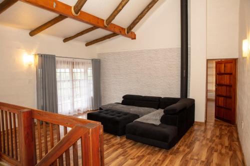 a living room with a black couch and a table at Riverbend Berg Lodge in Bergville