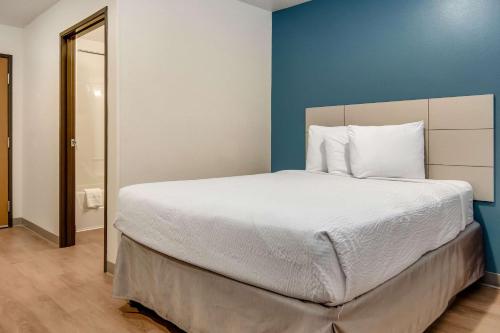 a bedroom with a large bed with a blue wall at WoodSpring Suites Abilene in Abilene