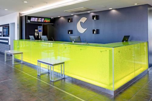 a yellow counter in a lobby with two tables at Comfort Hotel Central International Airport in Tokoname