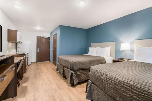 a hotel room with two beds and a blue wall at WoodSpring Suites Charlotte - University Research Park in Charlotte