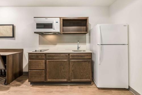 a kitchen with a white refrigerator and a sink at WoodSpring Suites Charlotte - University Research Park in Charlotte