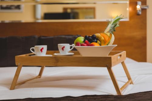 ein Tablett mit einer Schale Obst und Tassen auf einem Bett in der Unterkunft Hotel Podgorica in Podgorica