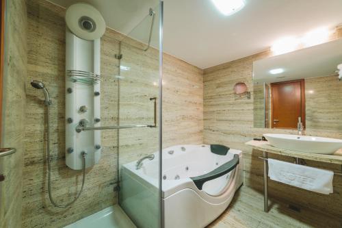a bathroom with a tub and a sink at Hotel Podgorica in Podgorica