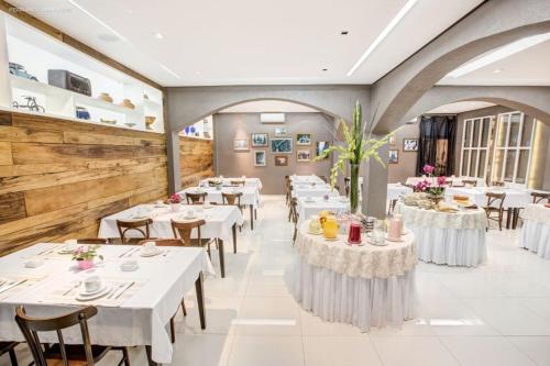 a dining room with white tables and chairs at Almasty Hotel in Chapecó