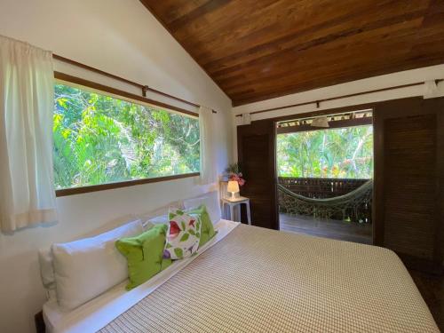 a bedroom with a bed and a large window at Pousada Big Bambu in Trancoso