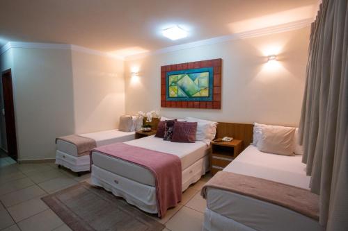 a room with two beds and a painting on the wall at Havana Express in Uberaba