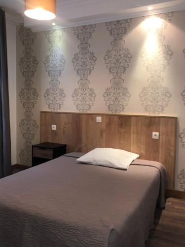 a bedroom with a bed and a wall with wallpaper at Hôtel Résidence Champerret in Levallois-Perret