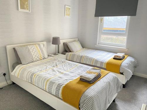 a bedroom with two beds and a window at Paisley Central Apartment #2 in Paisley