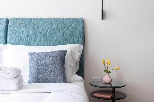 a bedroom with a bed with a blue headboard and a table at BMORE Apartments in Milan