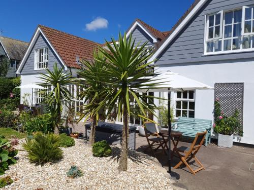 a house with a palm tree and a table and chairs at Falmouth Bay Holiday Apartments in Falmouth