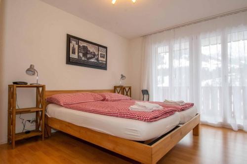 a bedroom with a large bed with red and white sheets at Ferienwohnung Margeli in Adelboden