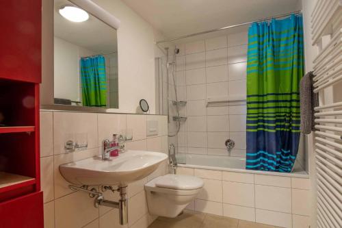 a bathroom with a sink and a toilet and a tub at Ferienwohnung Margeli in Adelboden