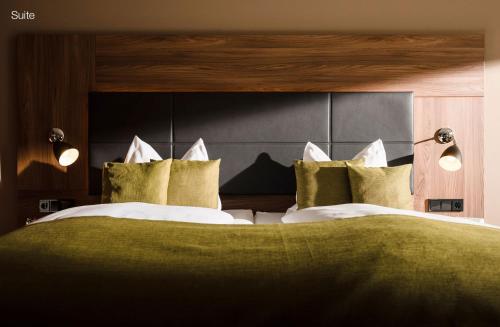 a bedroom with a large bed with green sheets and pillows at Sporthotel Grafenwald 4 Sterne Superior in Daun