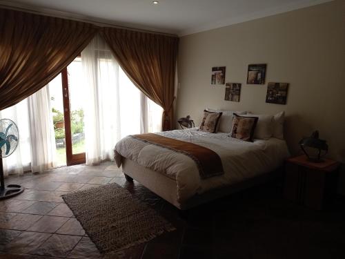 a bedroom with a bed and a large window at Troas Boutique hotel in Vanderbijlpark