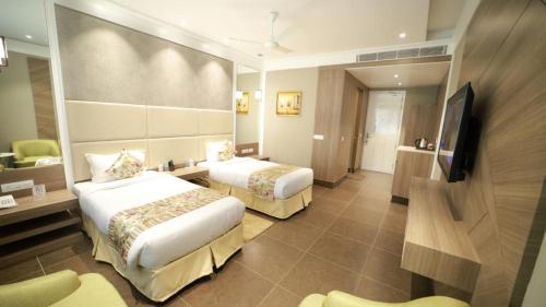 a hotel room with two beds and a flat screen tv at THE GRAND VILLAGE in Morādābād