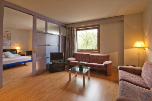 een woonkamer met een bank, een tv en een bed bij Hotel Domo in Vilafranca del Penedès