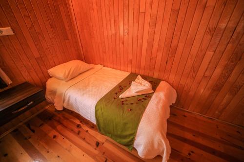 a small bedroom with a bed in a wooden room at Cirali Zakkum Bungalow in Cıralı