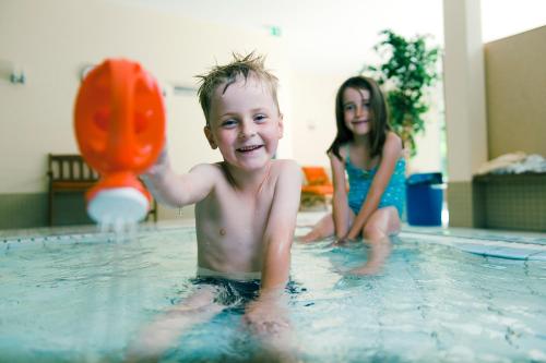a young boy and girl playing in a swimming pool at Sporthotel Grafenwald 4 Sterne Superior in Daun
