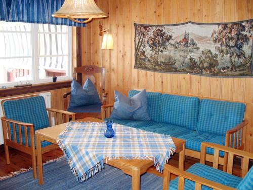 een woonkamer met een blauwe bank en een tafel bij Chalet Forsviken - VMD049 by Interhome in Karlstad