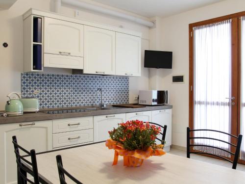 una cucina con armadi bianchi e un tavolo con fiori di Holiday Home Malva by Interhome a Bagni