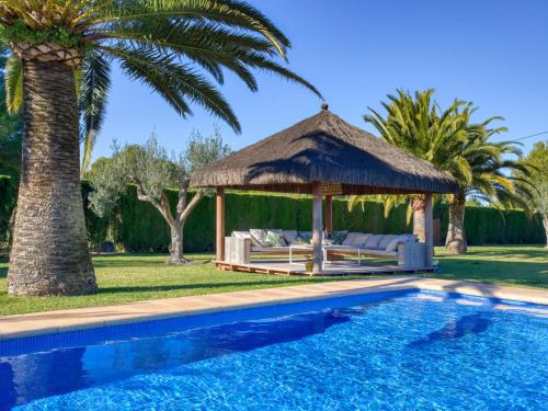 a pool with a gazebo and a palm tree at Holiday Home El Torrero by Interhome in Benitachell