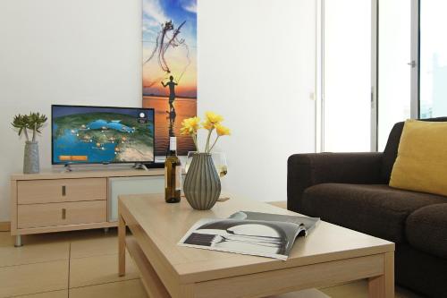 een woonkamer met een salontafel en een televisie bij Calypso - Coralli Beachfront Apartment in Protaras