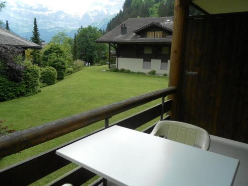 uma mesa branca e cadeira numa varanda com vista para um quintal em Apartment Ammerten A17 by Interhome em Lenk