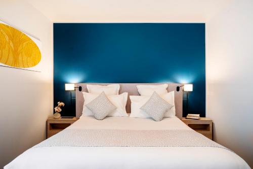 a bedroom with a bed with a blue headboard and pillows at Residhome Saint Ouen in Saint-Ouen