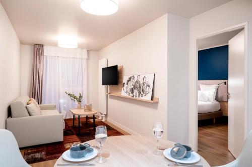 een woonkamer met een tafel en een kamer met een bed bij Residhome Saint Ouen in Saint-Ouen
