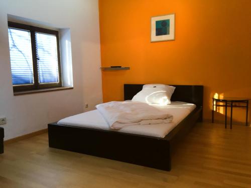 a bed in a room with an orange wall at Hotel ZweiLinden Meckenheim Bonn in Meckenheim