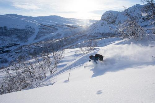 Eine Person fährt einen schneebedeckten Berg hinunter in der Unterkunft Skigaarden in Hemsedal