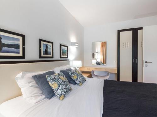 Cette chambre comprend un lit blanc avec des oreillers et un bureau. dans l'établissement Apartment Cala Sultana-7 by Interhome, à Usciolo