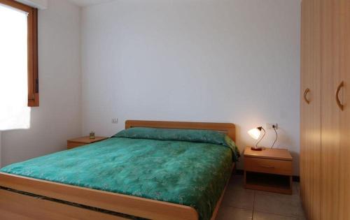 a bedroom with a bed with a green comforter at UR-NEST Fantin in Bologna