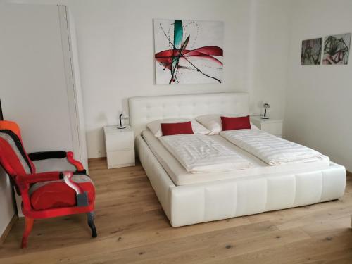 1 dormitorio con 1 cama blanca y 1 silla roja en Schneiders Ferienhaus Pulkau, en Pulkau