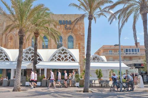 people walking in front of a building with palm trees at Villa Can Pastilla in Can Pastilla