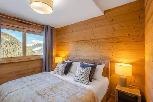 - une chambre avec des murs en bois et un lit avec des oreillers dans l'établissement Chalets de Vonnes 8 - Appartement - BO Immobilier - Châtel - Châtel Multipass Été 2025 en option au tarif de 3euros par jour et par personne, à Châtel